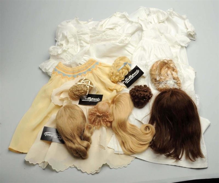 LOT OF DOLL DRESSES AND WIGS.                     