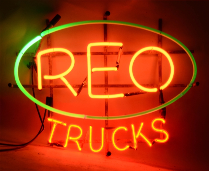 REO TRUCKS NEON SIGN ON ORIGINAL METAL HANGING RACK.