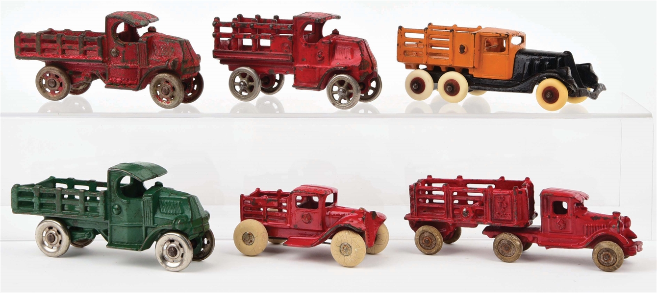 LOT OF 6: CAST-IRON AMERICAN MADE STAKE BACK TRUCKS.