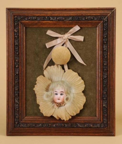 CARVED WALNUT FRAME WITH GERMAN BISQUE DOLL HEAD  