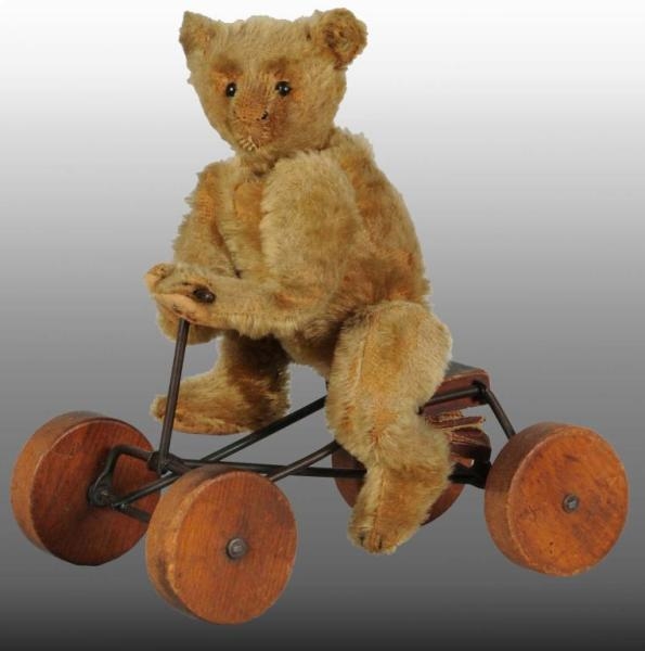 EARLY STEIFF TEDDY BEAR ON TOY BICYCLE.           