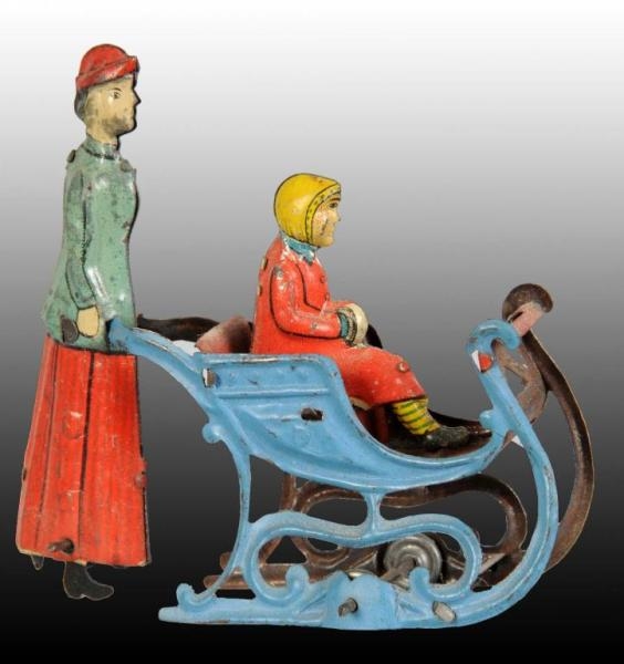TIN WOMAN PUSHING GIRL IN SLED PENNY TOY.         