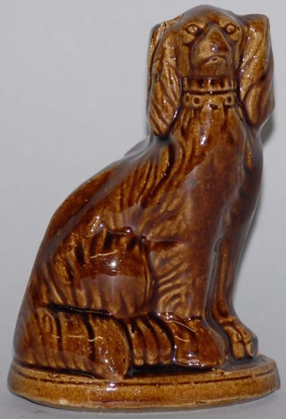BROWN POTTERY SEATED DOG STILL BANK.              