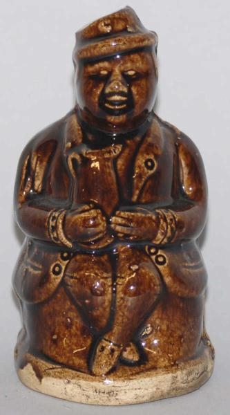 POTTERY SEATED MAN WITH CROSSES LEGS STILL BANK.  
