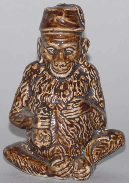 BROWN POTTERY SEATED MONKEY STILL BANK.           