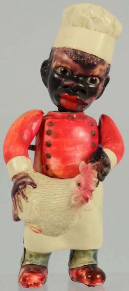 CELLULOID FIGURE OF BLACK COOK HOLDING CHICKEN.   
