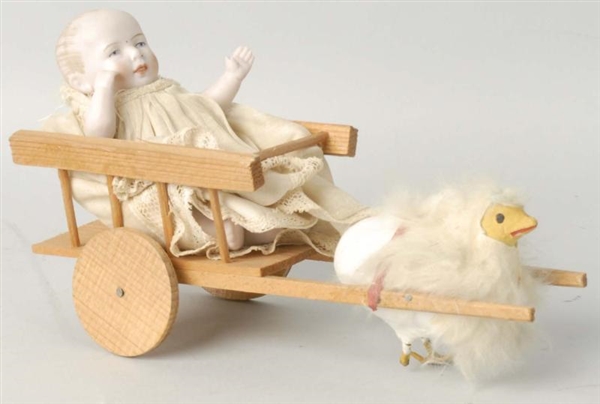 JOINTED BISQUE BABY IN WOODEN CART.               