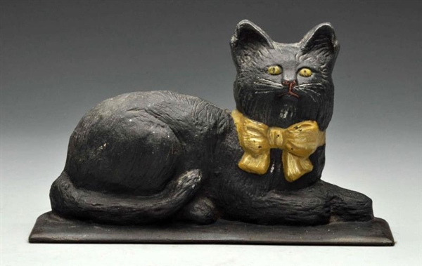 CAST IRON LYING DOWN CAT WITH BOW DOORSTOP.       