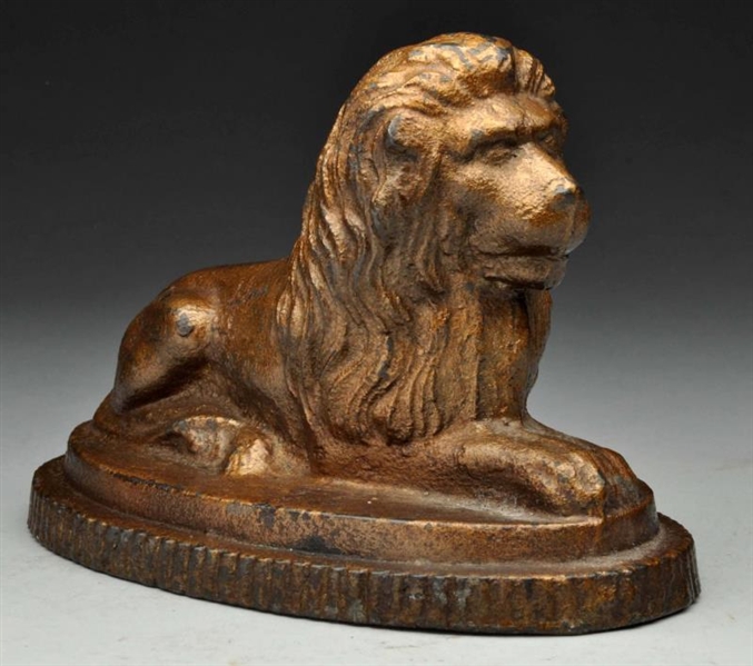 CAST IRON LAYING LION ON OVAL PEDESTAL DOORSTOP.  