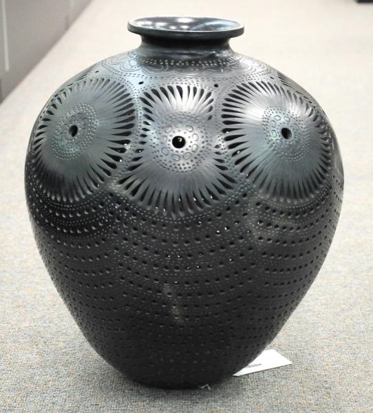 DECORATIVE CARVED METAL URN ON WOVEN STAND.       