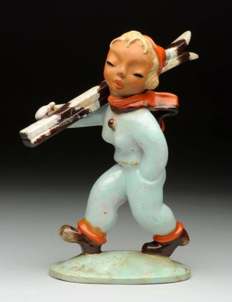 FIGURINE OF GIRL CARRYING SKIS.                   