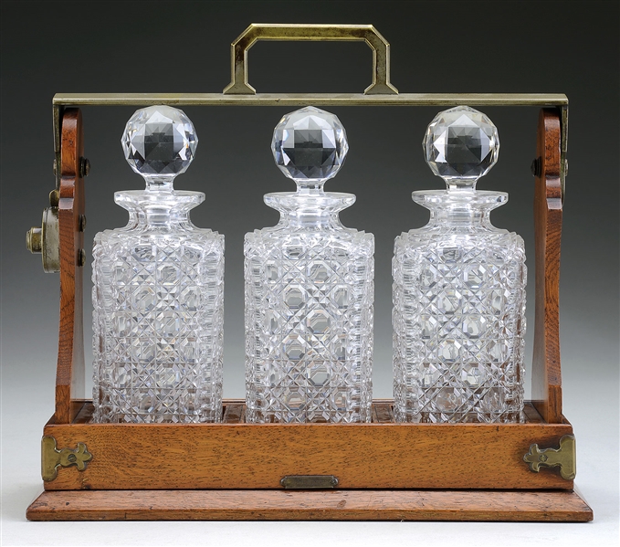 OAK CASED TANTALUS WITH THREE STOPPERED CUT GLASS DECANTERS.                                                                                                                                            