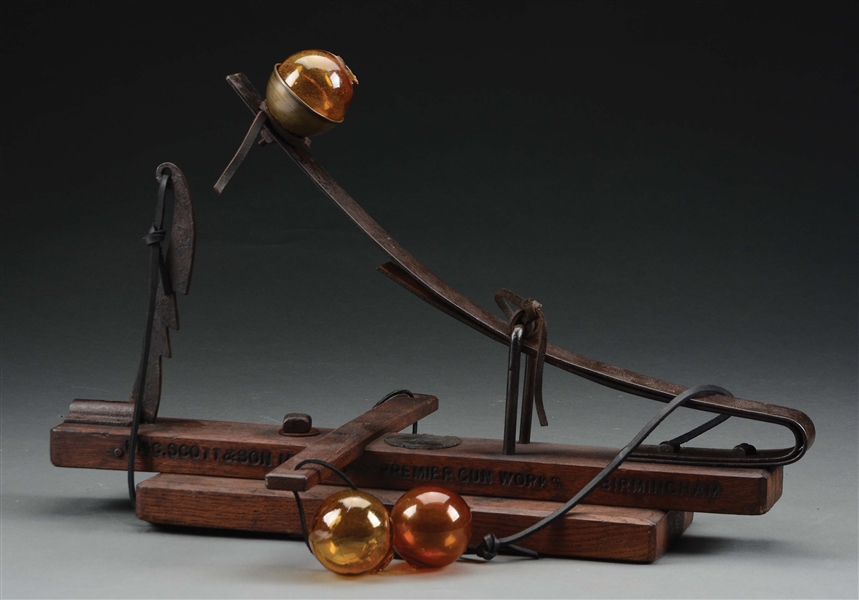 CAPTAIN BOGARDUS GLASS BALL THROWER WITH THREE AMBER BALLS.
