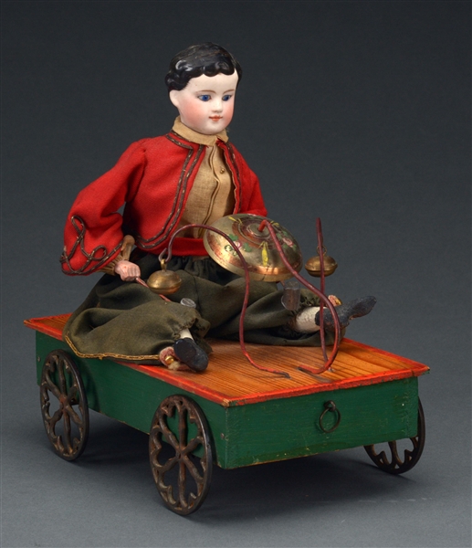 SEATED CHILD ON WHEELED PLATFORM BELL TOY.