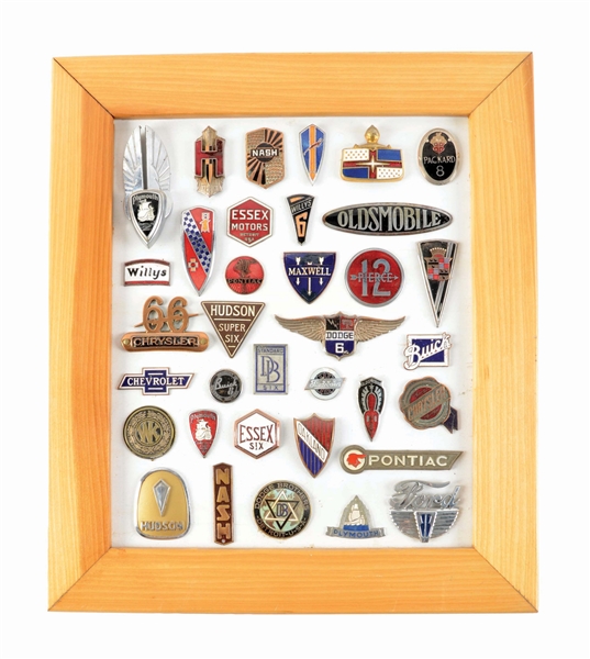 COLLECTION OF 35 VARIOUS MOTOR CAR BADGES & EMBLEMS MOUNTED ON WOOD W/ FRAME. 