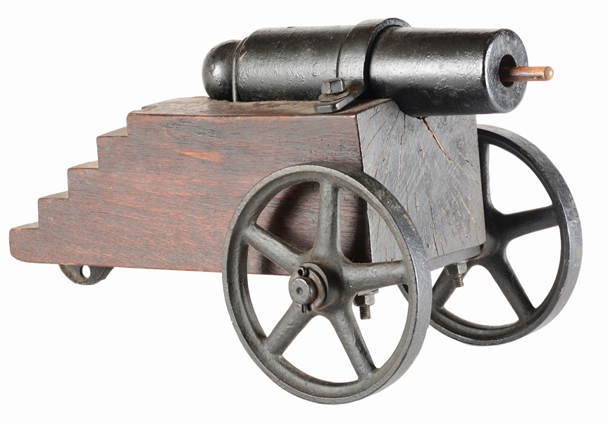 IRON CANNON ON LAYERED WOOD CARRIAGE AND CAST IRON WHEELS.