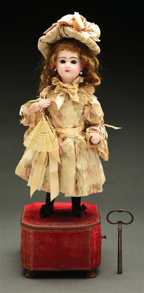 FRENCH BISQUE DOLL AUTOMATON ON RED VELVET BASE.